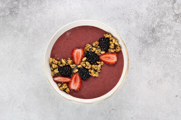 Obraz na płótnie Canvas Smoothie bowl with strawberries, blackberries and granola on a gray background. Healthy breakfast. Top view. 