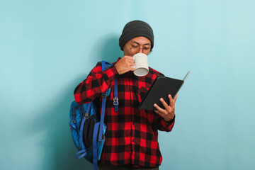 Young Asian male student takes a coffee break after lectures, isolated on blue background