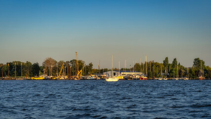 Shipyard and harbour of Szczecin Dabie marina with moored yachts and boats at sunset. Cranes and...