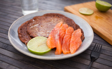 Salted salmon fillet with buckwheat pancakes and lime