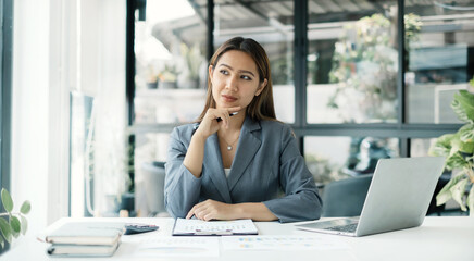 Asian businesswoman sit at their desks and calculate financial graphs showing results about their...