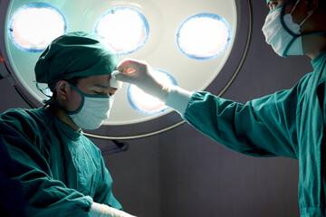 Professional surgical team operating surgery patient, medical staff wiping the sweat to surgeon...