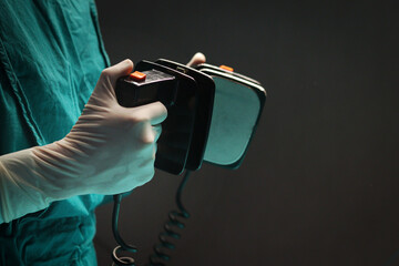 Surgeon doctor hand hold defibrillator to pump chest heart patient to save life sick people in...