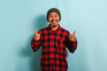 Confident Young Asian man showing a thumbs-up gesture, isolated on a blue background