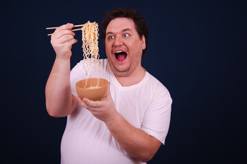 Funny fat man on a diet eating Chinese noodles. Blue background.