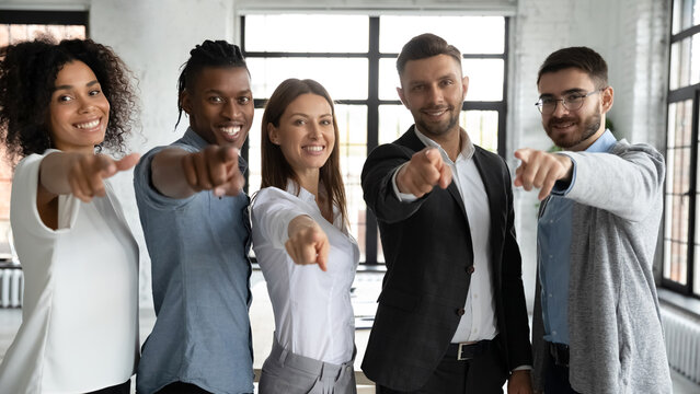 Portrait of smiling multiracial employees look at camera point at screen with finger make choice decision, happy multiethnic diverse team choose candidate applicant, employment, recruitment concept