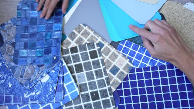 Two hands pointing on different swatches of pvc lining for pool covering choosing design of swimming pool