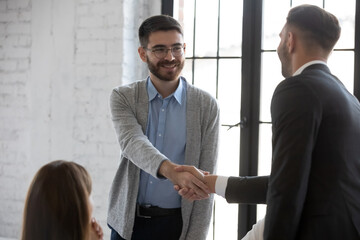 Businessman shake hand greeting get acquainted with smiling male employer at meeting, business...