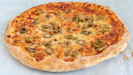 Homemade pizza with cheese and green olives.
