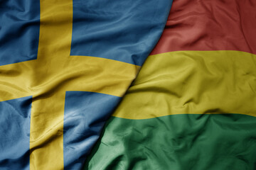 big waving national colorful flag of sweden and national flag of bolivia .