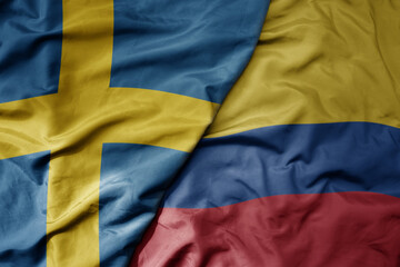 big waving national colorful flag of sweden and national flag of colombia .