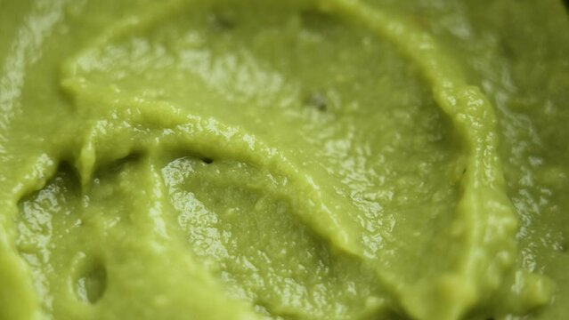 Fresh avocado cream. Guacamole paste of mashed green fruits. Healthy food. Macro shot. Rotation