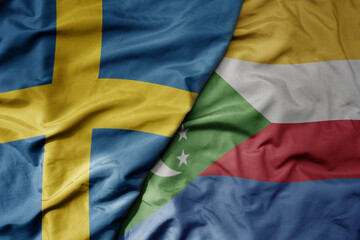big waving national colorful flag of sweden and national flag of comoros .