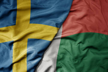 big waving national colorful flag of sweden and national flag of madagascar .