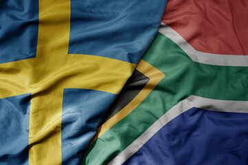big waving national colorful flag of sweden and national flag of south africa .