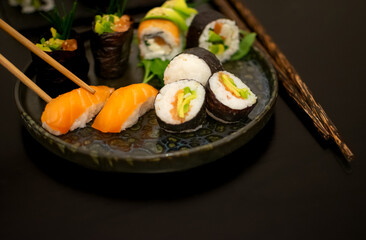 Chopsticks taking Luxury Sushi Nigiri, creatively plated with Gunkan and Uramaki
