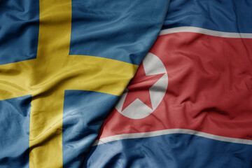 big waving national colorful flag of sweden and national flag of north korea .