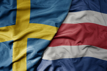 big waving national colorful flag of sweden and national flag of costa rica .