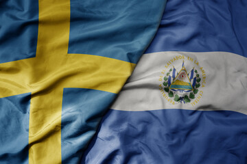 big waving national colorful flag of sweden and national flag of el salvador .