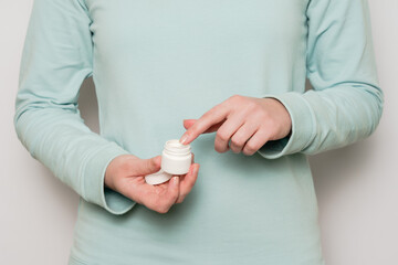 Plastic jar (container) in a woman's hands. Cosmetic product.
