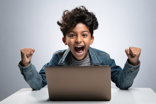 Indian little boy excited and giving winning gesture while using laptop