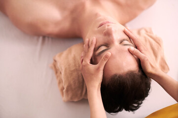 Fototapeta premium Beautician giving man relaxing and rejuvenating face massage
