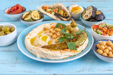 Hummus plate on the background of traditional appetizers for Israeli snack.