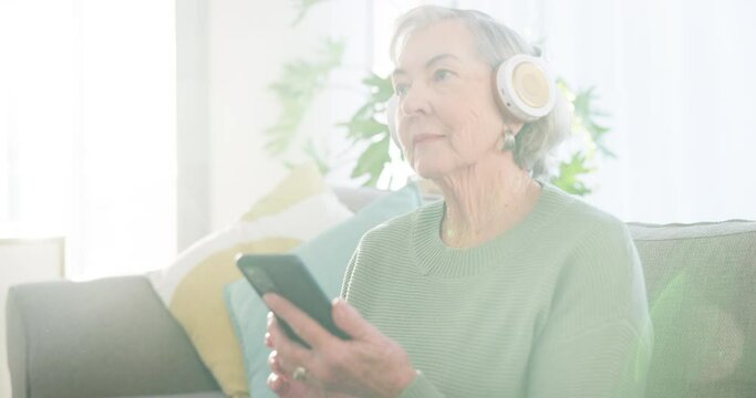 Senior woman, phone and music headphones in home for listening to audio, radio and podcast on sofa. Happy elderly lady dancing with smartphone for streaming sound online, media app and subscription