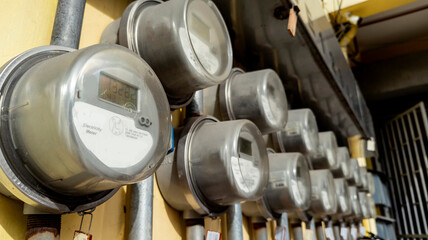 Several digital electric meters installed on the wall at an apartment building or other commercial...