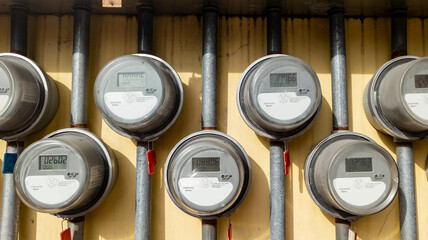Several digital electric meters installed on the wall at an apartment building.
