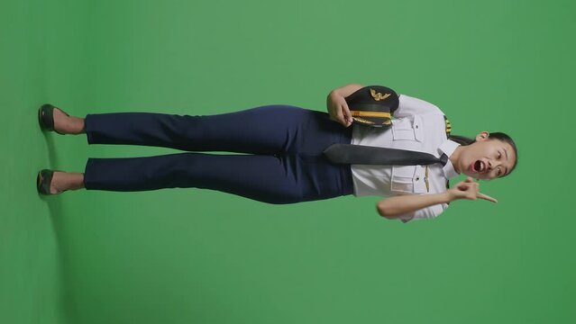 Full Body Of Asian Woman Pilot Thinking And Looking Around Then Raising Her Index Finger While Standing In The Green Screen Background Studio
