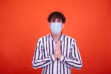 Funny curly guy posing in the studio on an orange background. Illness and protection against colds.