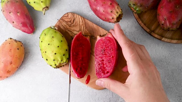 Prickly pears, exotic cactus fruits, female hands cut cactus fruit in halves