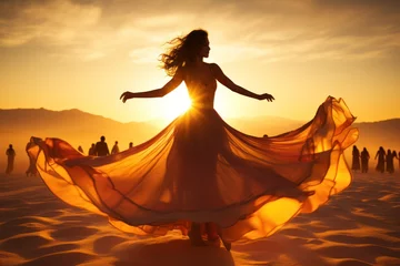 Gardinen Beautiful woman in a long dress dancing in the desert at sunset © tanatat
