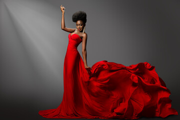 Beautiful Woman dancing in Red waving Dress on Stage. Fashion Dark Skin Model in long Gown Side View. Stylish Girl with Afro hair Style over Gray Background - 646020107