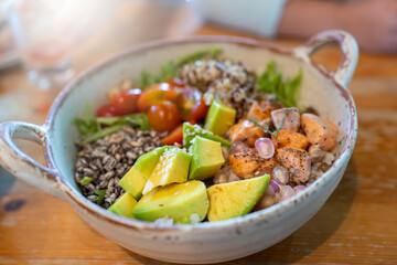 Grilled salmon salad in white bowl on wooden table. Healthy lunch food.