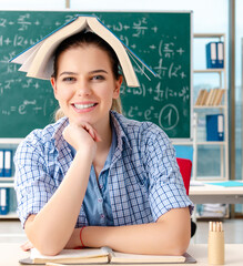 Female student with many books sitting in the classroom