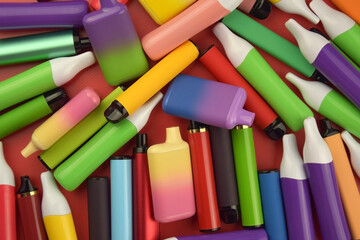 Set of multicolor disposable electronic cigarettes on a red background.