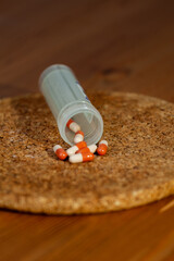 Two-colored tablets come out of the plastic tube. The medicine fell onto a cork circle placed on the table.