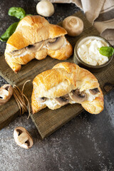 Croissant with cream cheese and mushroom on a stone background. French pastry, tasty freshly baked sandwich. Vegan food style. Copy space.