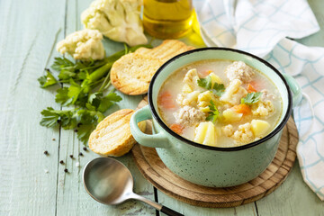 Cauliflower soup with chicken meatballs and vegetables on a wooden rustic table. Low carb healthy eating. Copy space.