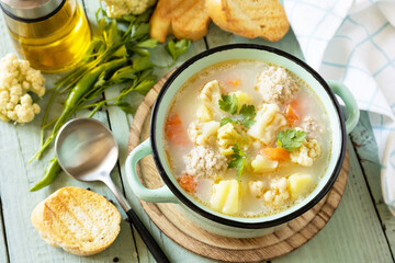 Cauliflower soup with chicken meatballs and vegetables on a wooden rustic table. Low carb healthy eating.