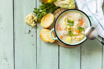 Cauliflower soup with chicken meatballs and vegetables on a wooden rustic table. Low carb healthy eating. View from above. Copy space.