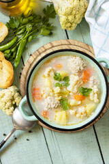 Low carb healthy eating. Cauliflower soup with chicken meatballs and vegetables on a wooden rustic table. View from above. Copy space.