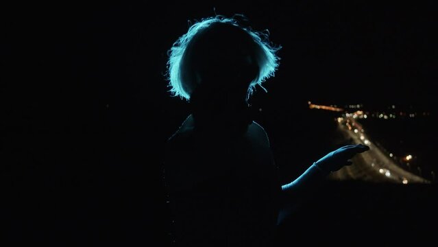 Silhouette of a dancing drag queen at night