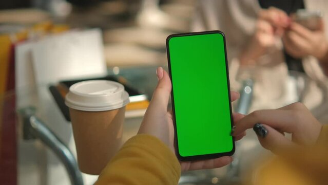 Use green screen for copy space closeup. Chroma key mock-up on smartphone in hand. Woman holds mobile phone and swipes photos or pictures left indoors of cozy home
