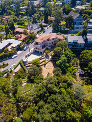 Fototapeta premium Aerial view of the Los Feliz neighborhood with large houses in the hills and downtown Los angeles skyline in the background.