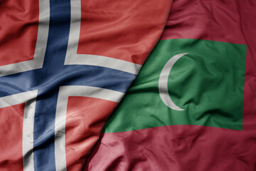 big waving national colorful flag of norway and national flag of maldives .