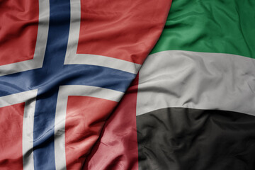 big waving national colorful flag of norway and national flag of united arab emirates .