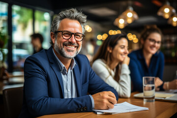 Impressive confident professional, expert in his field, chairing a cheerful meeting. Mature man, beard, glasses, suit, denotes trust and expertise.